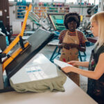 Shop workers using dye-sublimation and heat transfers with heat press